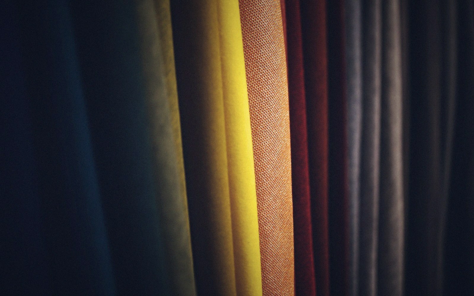 Rows of hanging fabric swatches in navy, olive, yellow, rust and burgundy tones