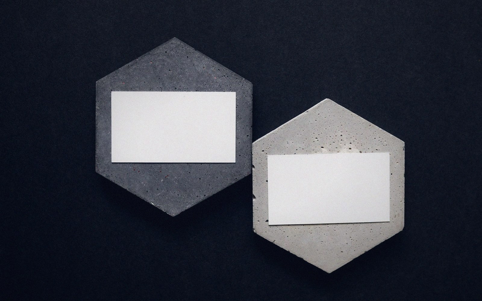 Two blank white cards resting on hexagonal concrete tiles of different shades